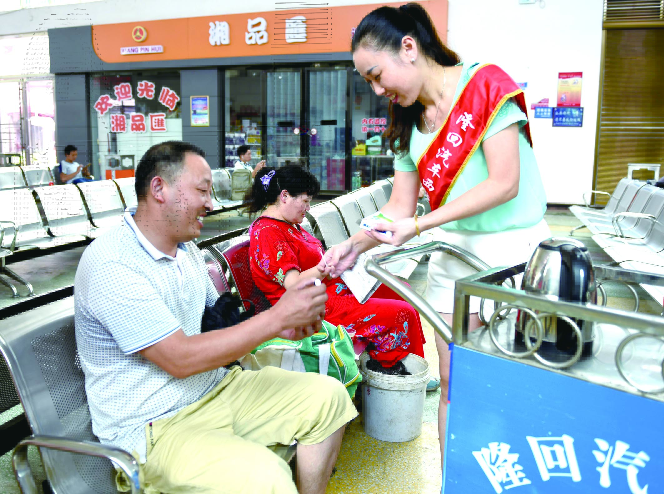 隆回分公司汽車西站工作人員正在為旅客免費贈送藿香正氣水。
